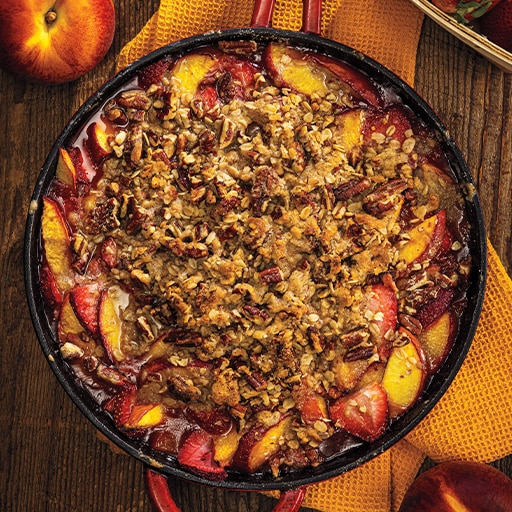 A skillet with assorted fruit placed on a wooden table