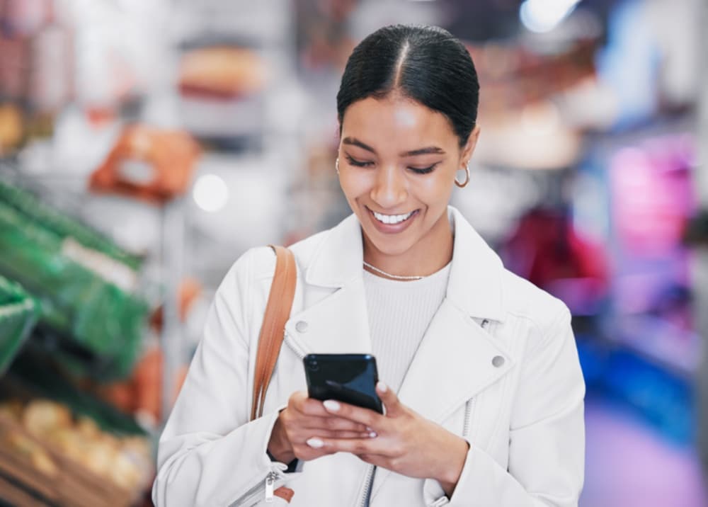 Shopper using mobile phone while browsing grocery store aisle