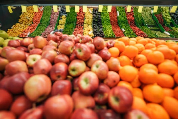Fresh produce display with apples, oranges, and vegetables in grocery store