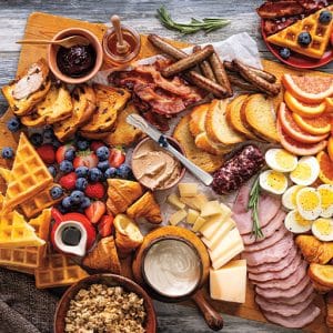 Picture of a Holiday brunch board featuring a variety of meats, cheese, bread and granola.