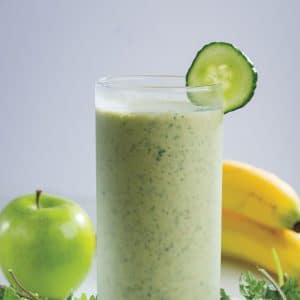 A healthy smoothie combining cucumber and apples, displayed in a glass with a bright green color and a straw.