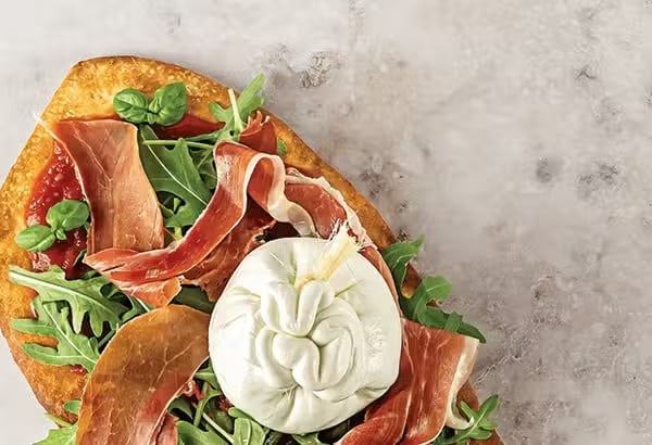 Flatbread with burrata, prosciutto, arugula, and tomato spread served in Ann Arbor, MI